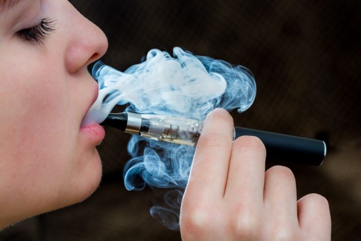 young woman with e-cigarette vapor
